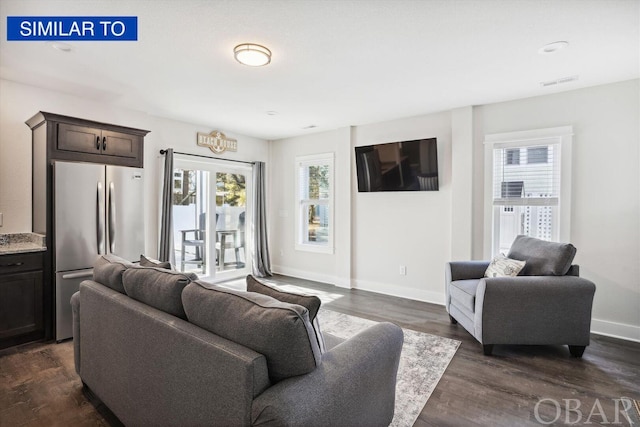 living room featuring dark wood-type flooring, visible vents, and baseboards