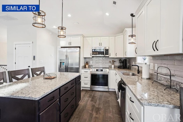 kitchen with a sink, a kitchen island, white cabinetry, hanging light fixtures, and appliances with stainless steel finishes