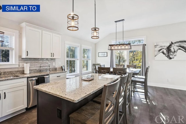 kitchen with white cabinetry, a kitchen breakfast bar, a center island, dishwasher, and pendant lighting