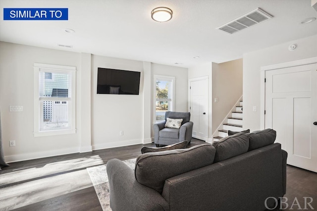 living room with visible vents, dark wood finished floors, baseboards, and stairs