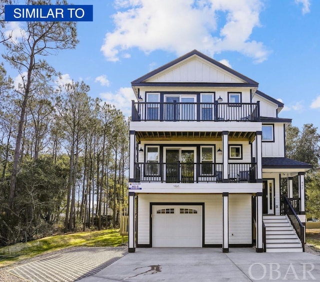 coastal inspired home with a balcony, driveway, and board and batten siding