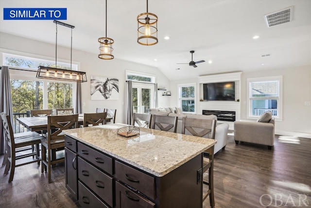 kitchen with visible vents, dark wood-type flooring, decorative light fixtures, and a glass covered fireplace