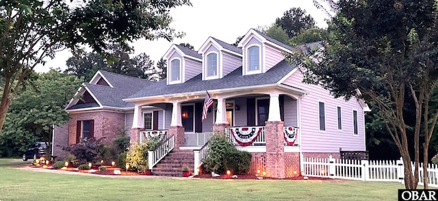 cape cod-style house with brick siding, fence, covered porch, stairs, and a front yard