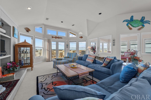 living room featuring visible vents, high vaulted ceiling, a wealth of natural light, and light colored carpet