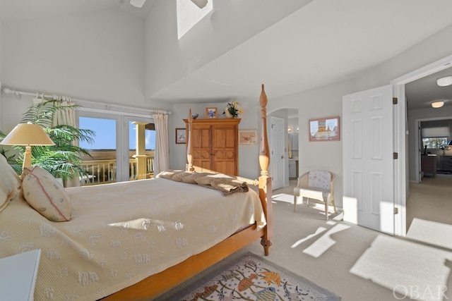 carpeted bedroom with high vaulted ceiling, arched walkways, and access to outside