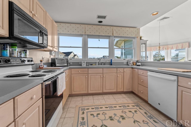 kitchen featuring white appliances, visible vents, decorative light fixtures, light brown cabinetry, and a sink