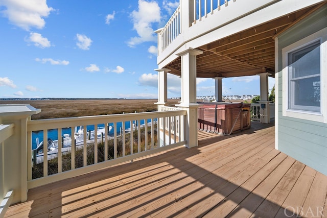 wooden terrace with a water view and a hot tub