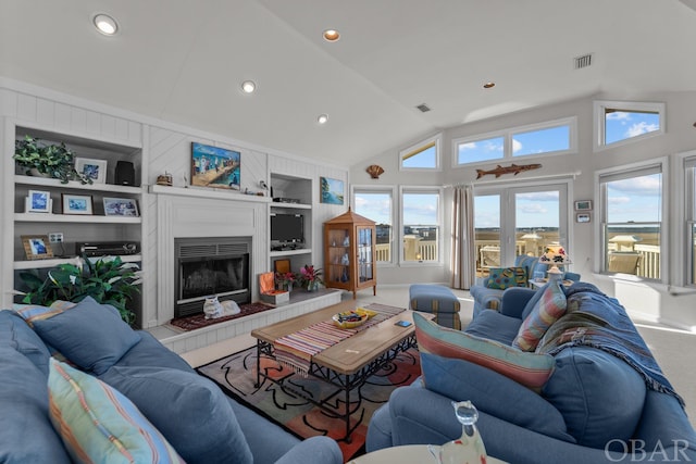 living room with carpet floors, visible vents, built in features, and a tiled fireplace