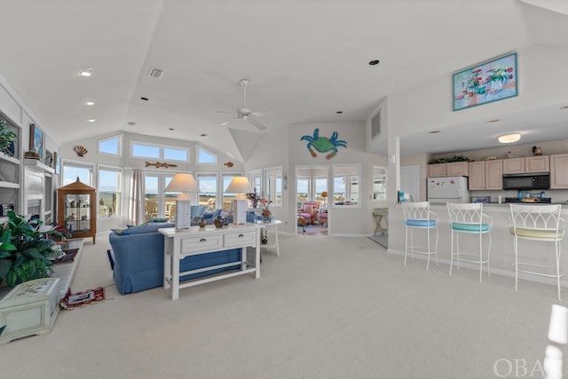 living room with high vaulted ceiling, light colored carpet, visible vents, and ceiling fan