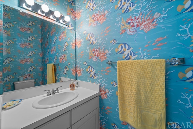 bathroom featuring vanity, toilet, and wallpapered walls