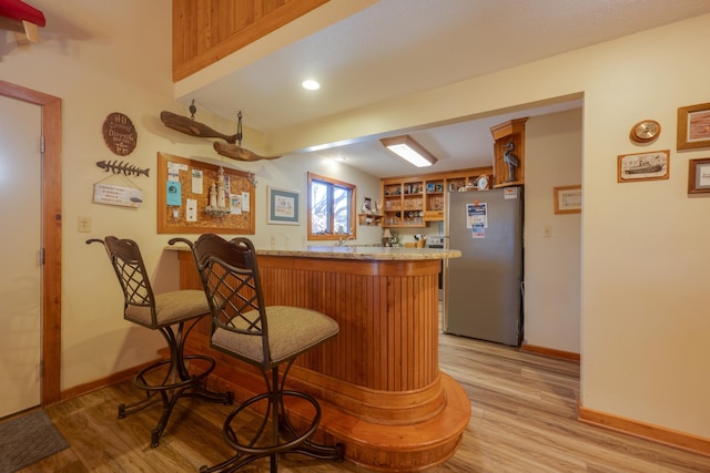 bar with freestanding refrigerator, baseboards, indoor bar, and light wood finished floors