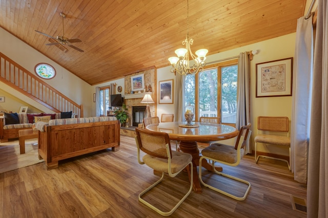 dining space with lofted ceiling, a fireplace, wood finished floors, wood ceiling, and stairway