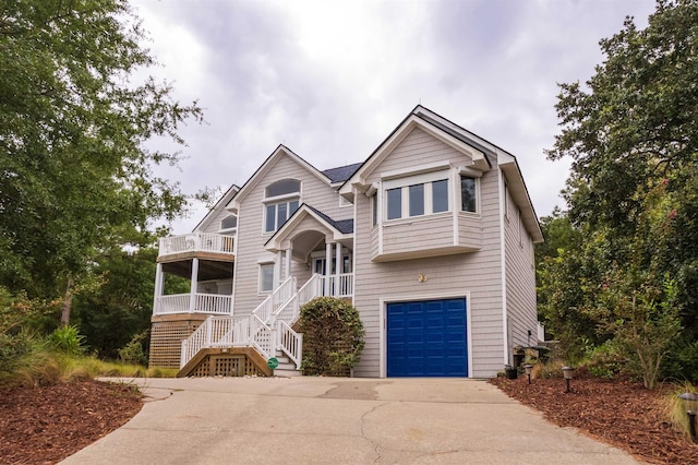 view of front of home with an attached garage, a balcony, stairs, and concrete driveway