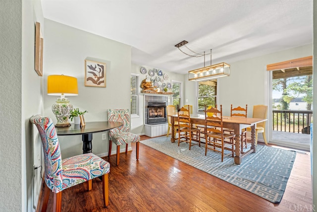 dining room with a tiled fireplace, wood finished floors, and baseboards