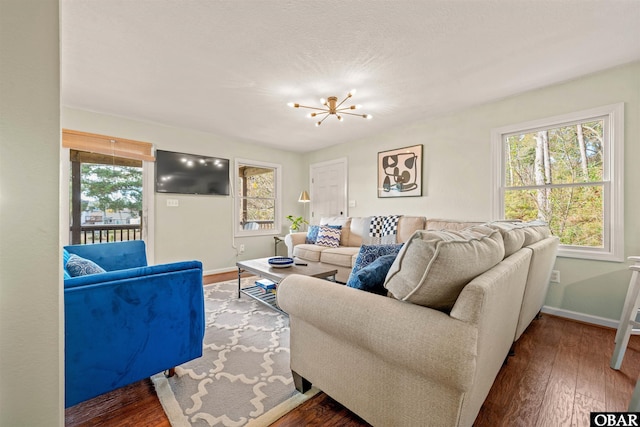 living area with a chandelier, baseboards, and wood finished floors