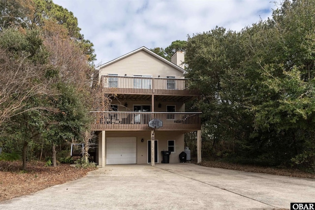 view of front of home with a chimney, concrete driveway, and a wooden deck