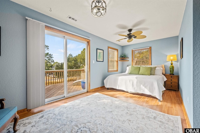 bedroom with baseboards, light wood finished floors, visible vents, and access to exterior