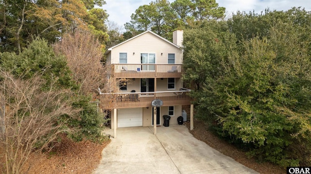 view of front of house featuring a garage, a balcony, a chimney, and concrete driveway