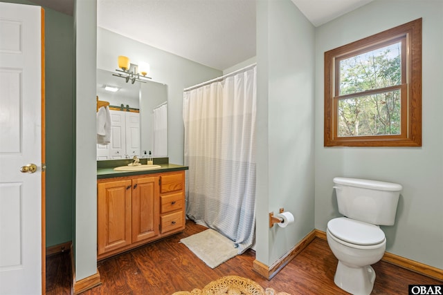 bathroom with toilet, baseboards, wood finished floors, and vanity