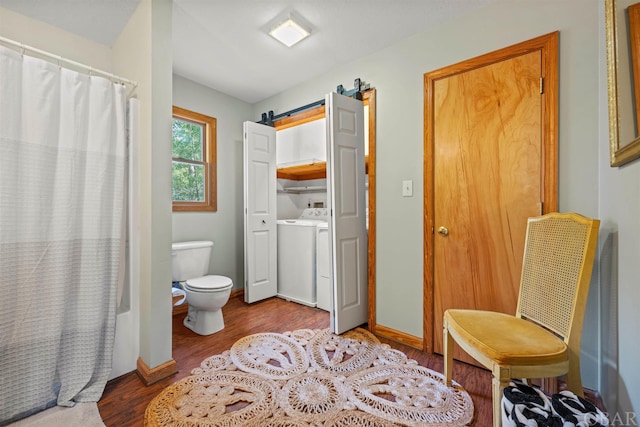 full bathroom with shower / bath combination with curtain, washer / clothes dryer, toilet, wood finished floors, and baseboards