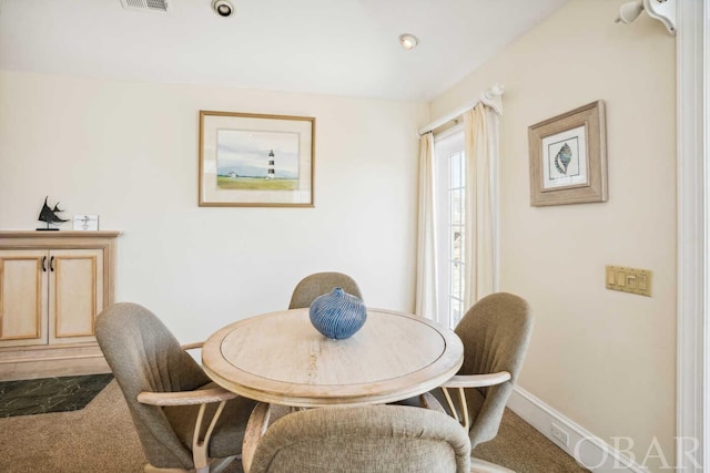 carpeted dining space with baseboards and visible vents