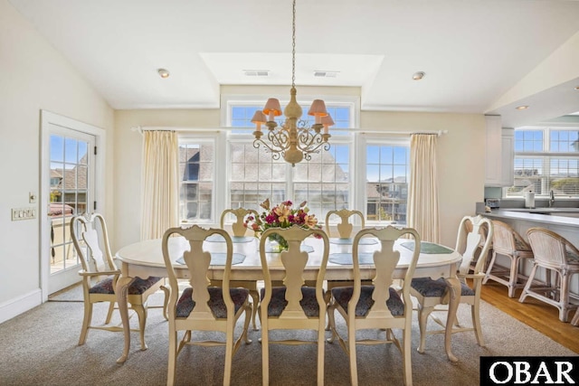 dining room featuring a chandelier, a healthy amount of sunlight, and vaulted ceiling