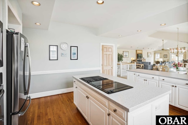 kitchen featuring open floor plan, a center island, freestanding refrigerator, black electric cooktop, and white cabinetry