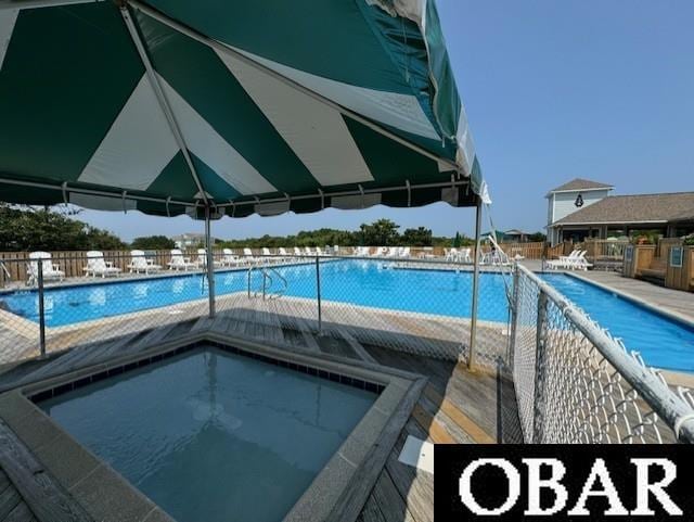 community pool with fence and a community hot tub