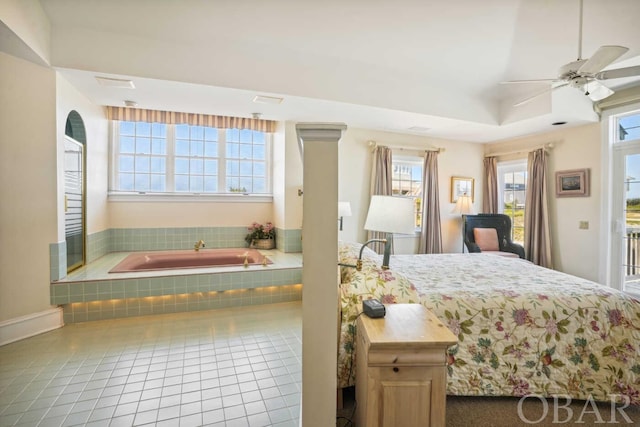 bedroom featuring access to exterior, a tray ceiling, a ceiling fan, and tile patterned floors