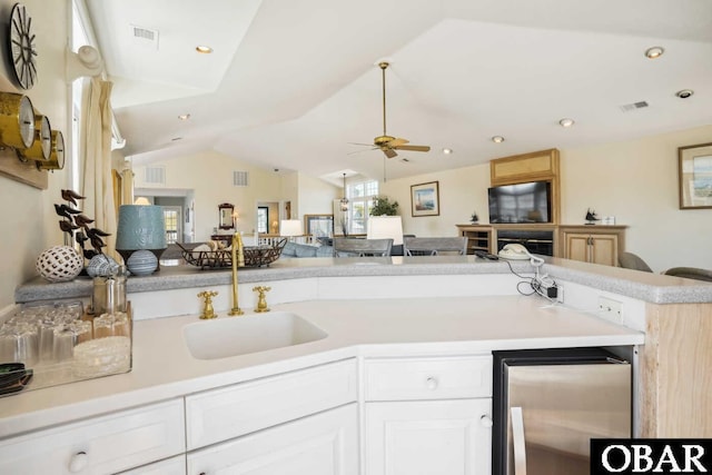 kitchen with light countertops, visible vents, freestanding refrigerator, open floor plan, and a sink