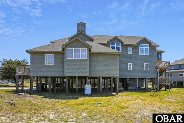 rear view of house with a carport, roof with shingles, a lawn, and a chimney