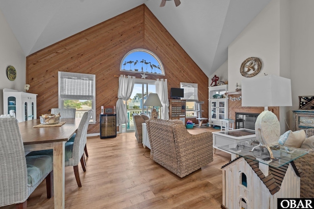 4121 W Whispering Winds Ct Lot 17, Nags Head, NC 27959 - living area with wooden walls, a glass covered fireplace, high vaulted ceiling, light wood-type flooring, and a ceiling fan