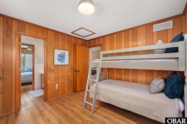 bedroom with visible vents, wood finished floors, ornamental molding, and wood walls