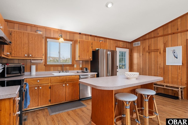 kitchen with visible vents, light countertops, vaulted ceiling, appliances with stainless steel finishes, and a sink