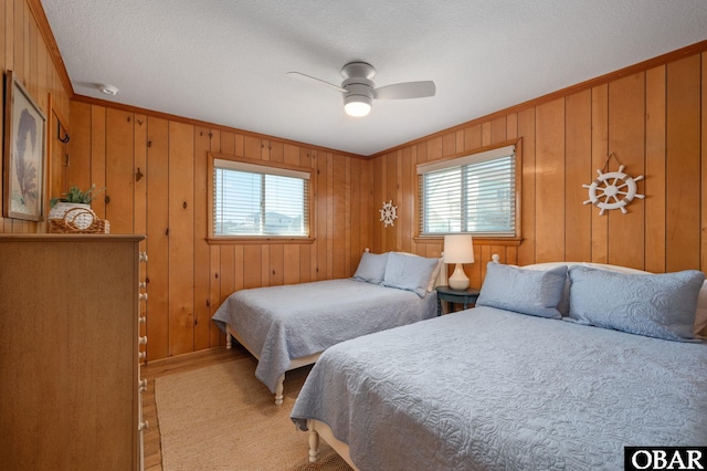 bedroom with light wood-style floors, ceiling fan, ornamental molding, and a textured ceiling