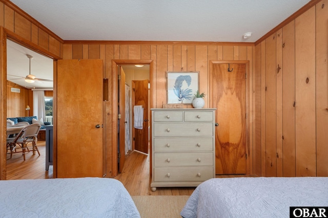 bedroom featuring visible vents, wood walls, crown molding, and light wood-type flooring