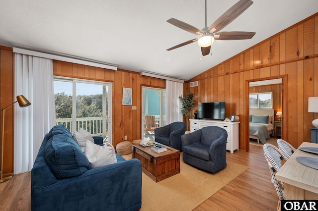 living room with vaulted ceiling, light wood finished floors, a ceiling fan, and a wealth of natural light