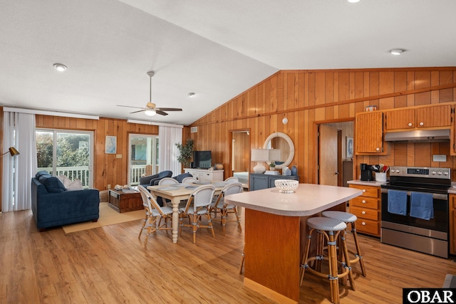 kitchen featuring stainless steel range with electric stovetop, light wood-style flooring, under cabinet range hood, light countertops, and lofted ceiling