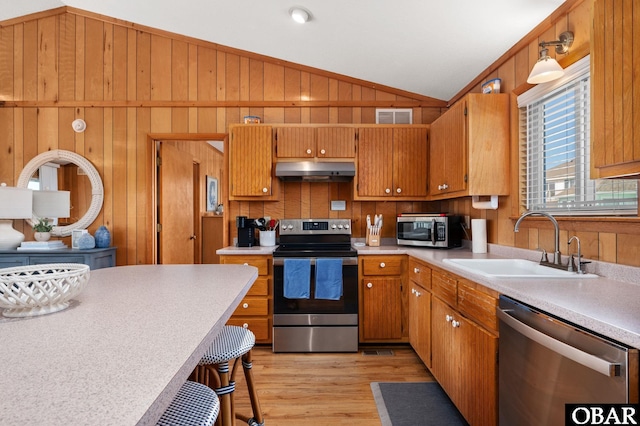 kitchen with visible vents, under cabinet range hood, a sink, stainless steel appliances, and vaulted ceiling