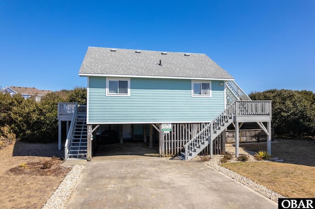 exterior space with driveway, stairway, roof with shingles, a front yard, and a carport