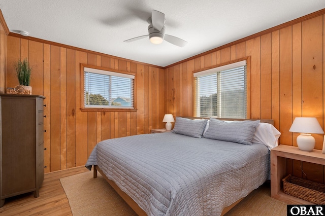 bedroom with multiple windows, light wood-style flooring, a ceiling fan, and ornamental molding