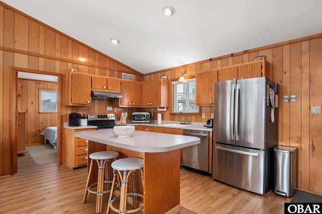 kitchen featuring lofted ceiling, a sink, stainless steel appliances, light countertops, and under cabinet range hood