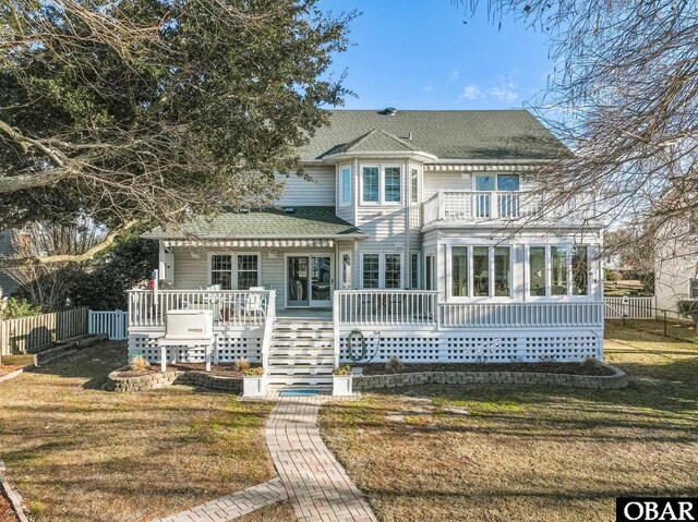 rear view of property featuring a sunroom, a shingled roof, fence, and a yard