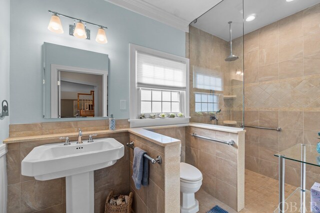 bathroom featuring toilet, ornamental molding, a walk in shower, and tile walls