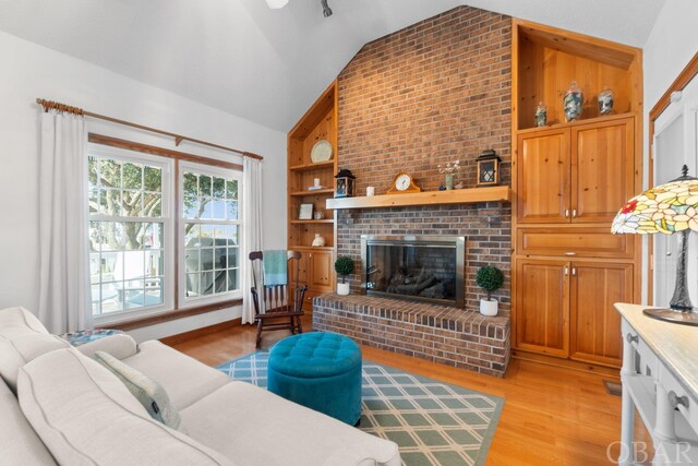 living room with lofted ceiling, light wood-type flooring, and a brick fireplace