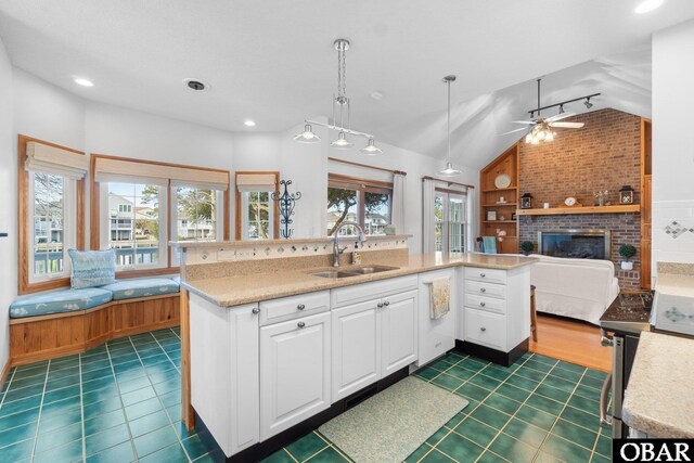 kitchen with open floor plan, a sink, decorative light fixtures, and white cabinets