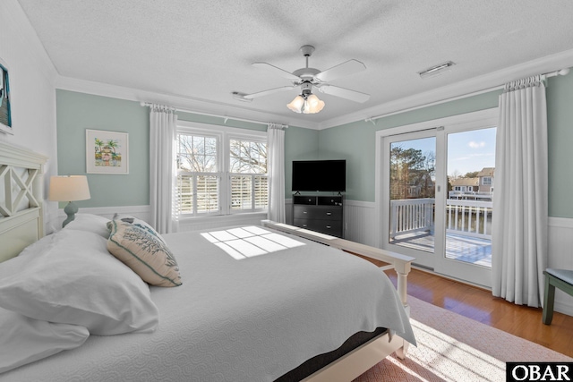 bedroom featuring access to outside, wainscoting, crown molding, and light wood finished floors