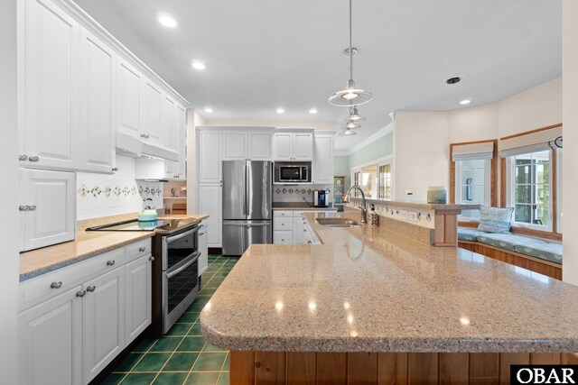 kitchen with stainless steel appliances, white cabinets, a sink, and a spacious island