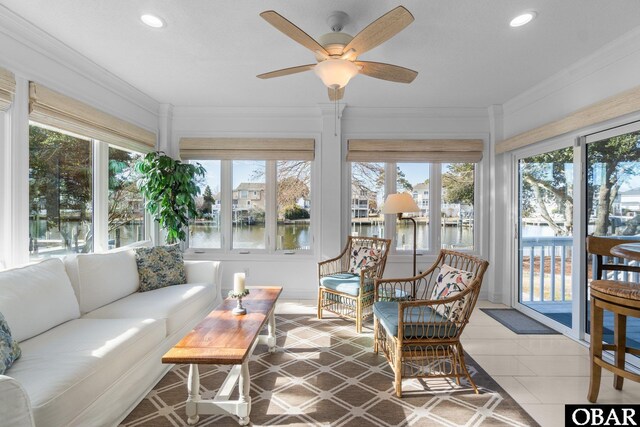 sunroom / solarium featuring a ceiling fan and a water view