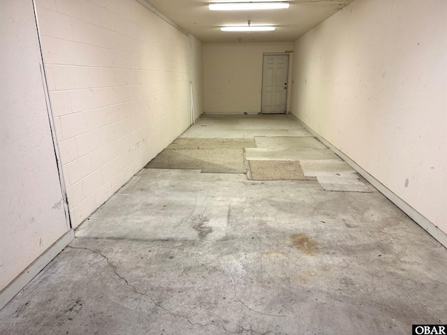 corridor with unfinished concrete flooring and concrete block wall